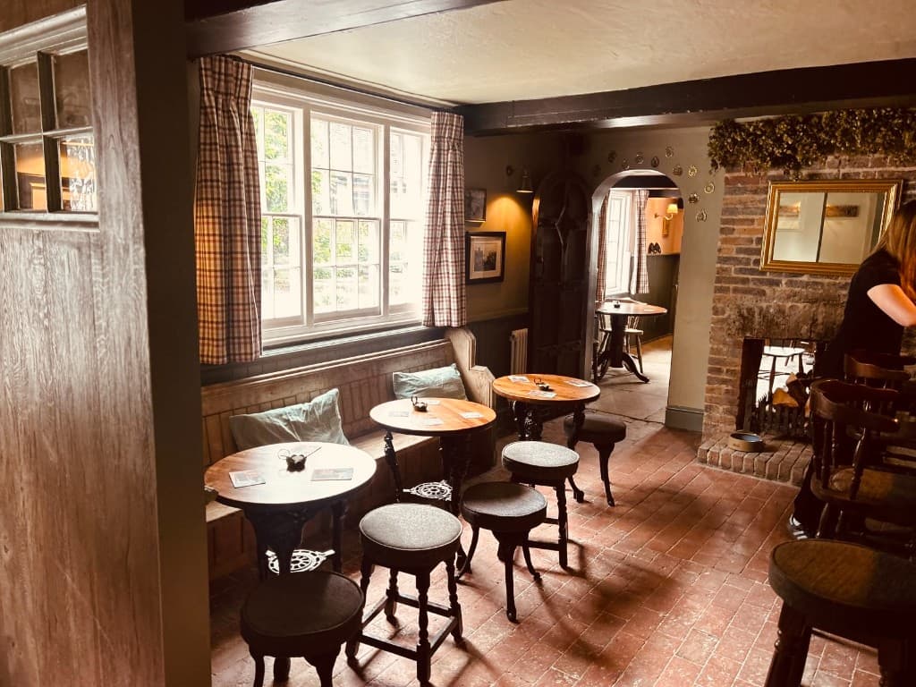 The snug at The Eight Bells — brick fireplace, hops and a wooden settle