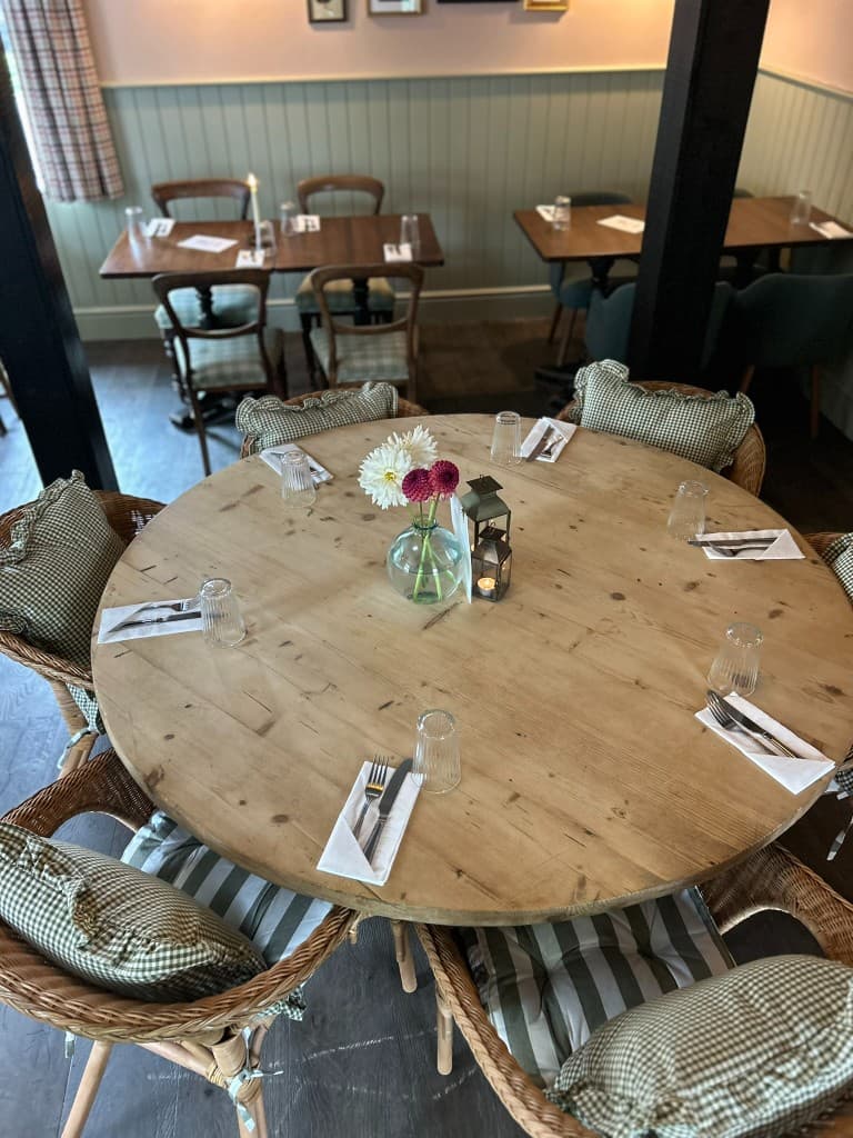 A round table set for six in the dining room at The Eight Bells