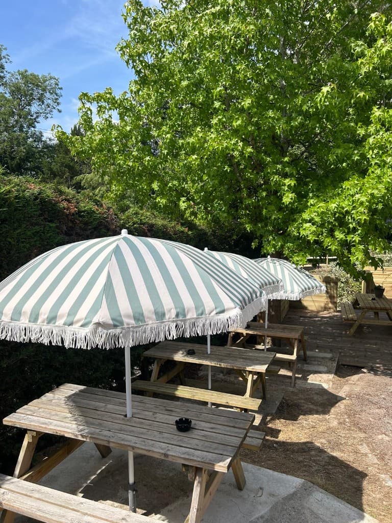 Garden picnic tables with sage-and-cream striped umbrellas at The Eight Bells